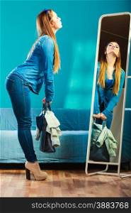 Fashion and shopping. Woman in full length wearing denim with bag. Attractive female shopper looking in mirror, standing in clothes store. Blue color