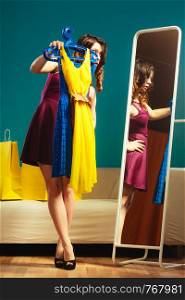Fashion and shopping. Woman preparing to party, trying dress choosing clothing. Attractive young woman shopper looking in mirror, standing in clothes store.