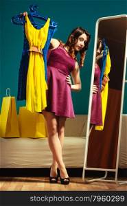 Fashion and shopping. Woman preparing to party, trying dress choosing clothing. Attractive young woman shopper looking in mirror, standing in clothes store.