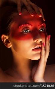 Fashion Art Concept. Beauty Woman Face with Red Painted Mask