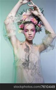 Fashion art photo of beautiful lady in flower diadem. Spring and summer portrait of young woman with real flowers in her hair.