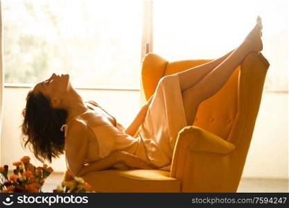 Fashion art photo of beautiful sensual woman in beige negligee in her boudoir. Home bedroom interior. Beautiful morning. Summer sunset