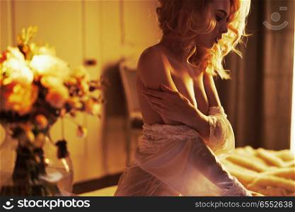 Fashion art photo of beautiful sensual woman in white negligee in her boudoir. Home interior. Beautiful morning. Summer sunset
