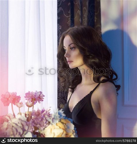 Fashion art photo of sensual lady with flowers. Home interior. Sunset