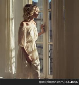 Fashion art portrait of beautiful blonde at the window