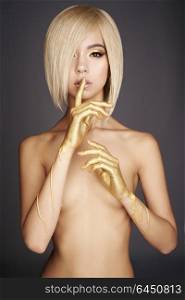 Fashion art studio photo of elegant nude asian woman with gold flowing down her hands. Fashion and beauty. Conceptual image. Bright makeup