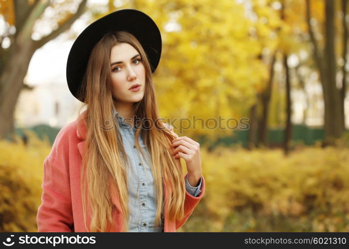 Fashion autumn portrait of stylish model woman, posing on the street, casual outfit, wearing denim shirt, leather skirt, vintage bright coat and black hat. Long hair, street style.