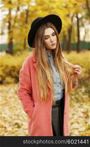 Fashion autumn portrait of stylish model woman, posing on the street, casual outfit, wearing denim shirt, leather skirt, vintage bright coat and black hat. Long hair, street style.