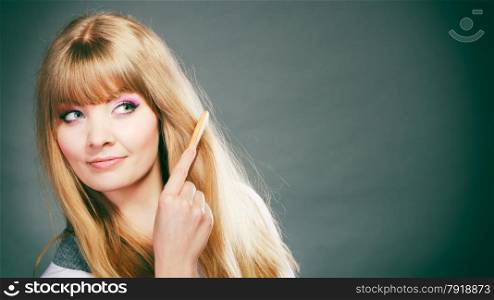 Fashion beauty and haircare concept. Blonde woman refreshing her hairstyle girl combing her hair with wooden comb gray background