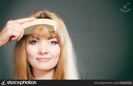 Fashion beauty and haircare concept. Closeup young woman refreshing her hairstyle girl combing her hair fringe with wooden comb