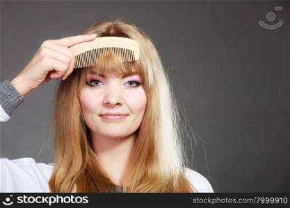 Fashion beauty and haircare concept. Closeup young woman refreshing her hairstyle girl combing her hair fringe with wooden comb
