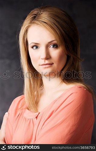 fashion beauty portrait of young woman with hair style over dark background wearing an orange shirt