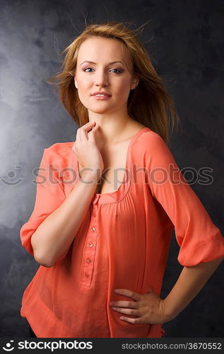 fashion beauty portrait of young woman with hair style over dark background wearing an orange shirt