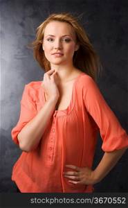 fashion beauty portrait of young woman with hair style over dark background wearing an orange shirt