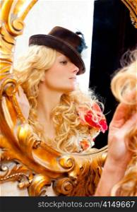 fashion blond woman with hat looking in baroque golden frame mirror