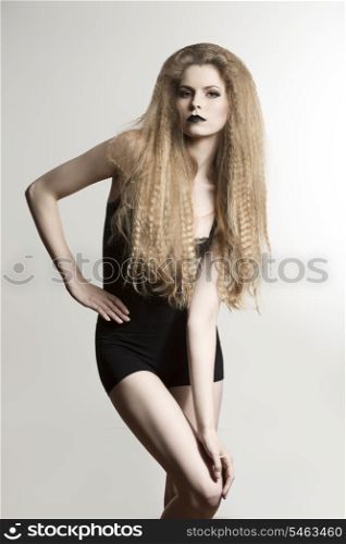 fashion blonde girl posing with long creative hair-style, black shorts and dark strong make-up.
