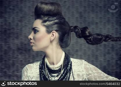 fashion brunette woman turned on profile in close-up portrait with creative hairdo and strong make-up. Wearing white lace shirt and a lot of necklaces