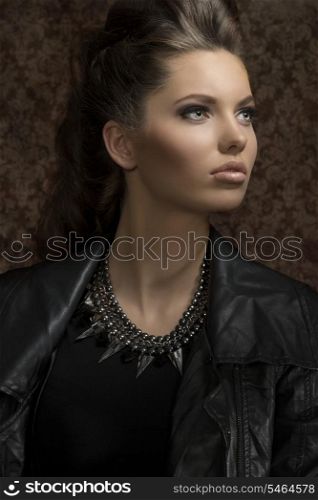 fashion close-up shoot of sensual young girl with modern gothic style and long brown hair wearing leather jacket and rock necklace