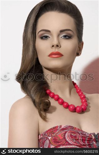 fashion close-up shoot of sexy woman with elegant hair-style, cute make-up and red necklace