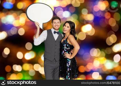 fashion, communication and holidays concept - happy couple hugging at party and holding blank text bubble banner over festive lights background. couple with text bubble over party lights . couple with text bubble over party lights