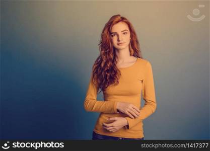 Fashion Concept - Headshot Portrait of happy ginger red hair girl with yellow sweater with confident face looking at camera. Pastel film blue background. Copy Space. Fashion Concept - Headshot Portrait of happy ginger red hair girl with yellow sweater with confident face looking at camera. Pastel film blue background. Copy Space.