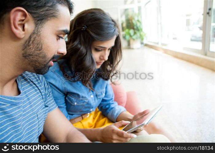 Fashion couple sitting together and using a tablet