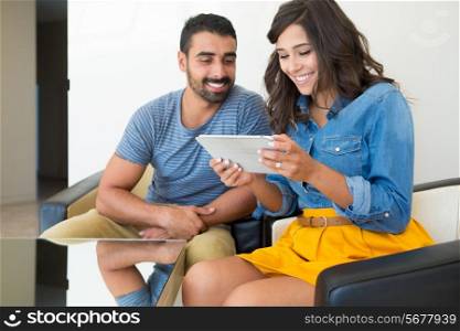 Fashion couple sitting together and using a tablet