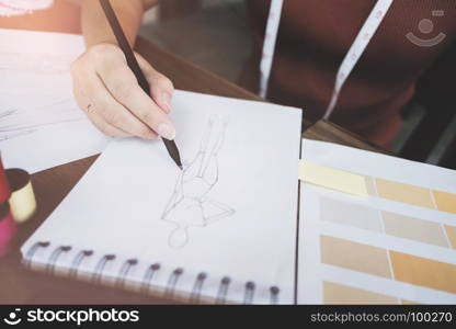 fashion / creative designer working with sketching notebook at modern home studio, selective focus