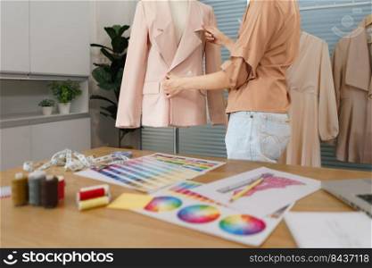 Fashion design concept, Asian female tailor is checking quality completeness of suit on mannequin.