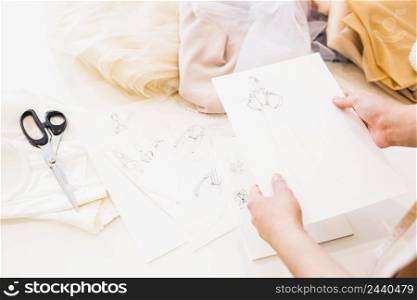 fashion designer holding sketches hand with many fabrics table