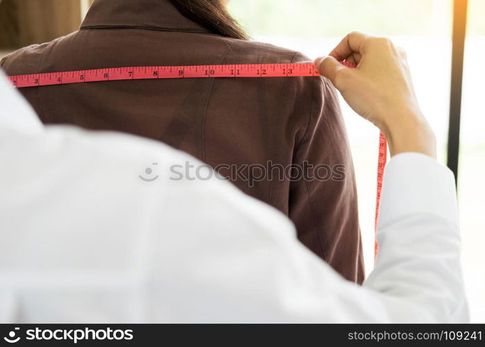 Fashion designer measuring on body part of women for a tailor made dress for a young business girl.