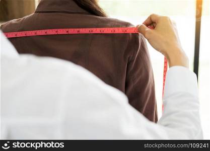 Fashion designer measuring on body part of women for a tailor made dress for a young business girl.
