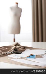Fashion designer studio with professional equipment, sketches, mannequin, cloth