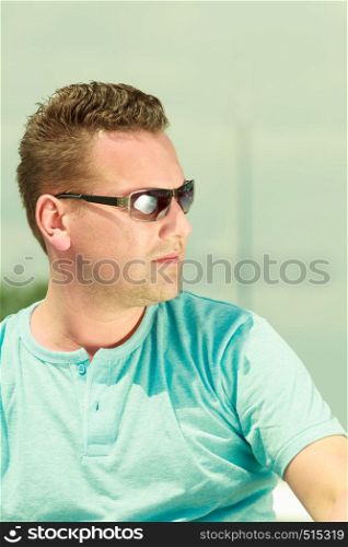 Fashion details and accessories concept. Portrait of handsome guy during summertime wearing blue tshirt and sunglasses.. Portrait of handsome guy during summertime