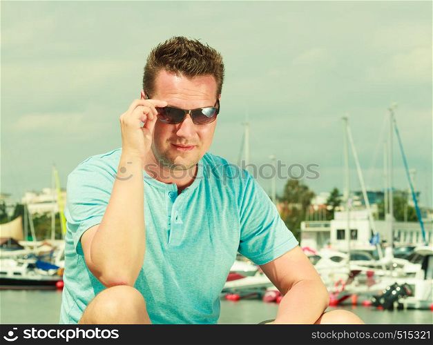 Fashion details and accessories concept. Portrait of handsome guy during summertime wearing blue tshirt and sunglasses.. Portrait of handsome guy during summertime