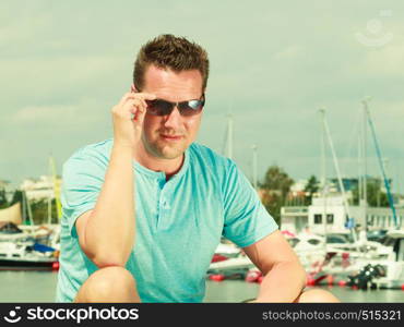 Fashion details and accessories concept. Portrait of handsome guy during summertime wearing blue tshirt and sunglasses.. Portrait of handsome guy during summertime