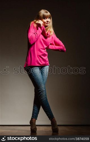 Fashion. Full body blonde fashionable woman jeans pants pink blouse. Female model posing dark background