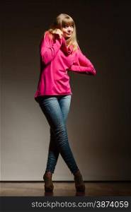 Fashion. Full body blonde fashionable woman jeans pants pink blouse. Female model posing dark background