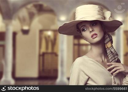 fashion girl with big elegant hat and foulard on the head posing with beige dress and sensual expression