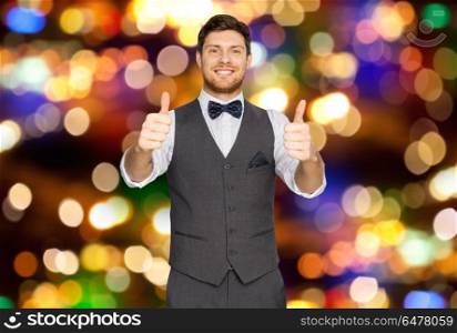 fashion, holidays and gesture concept - happy man in festive suit showing thumbs up over lights background. happy man in suit showing thumbs up over lights . happy man in suit showing thumbs up over lights