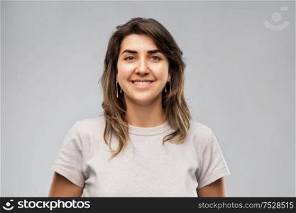 fashion, jewelry and people concept - happy smiling young woman in grey t-shirt and golden earrings. happy smiling young woman in grey t-shirt