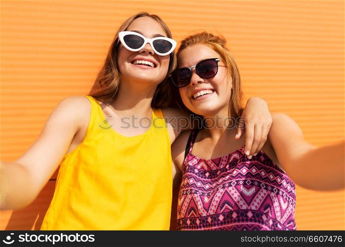 fashion, leisure and people concept - smiling teenage girls taking selfie outdoors in summer. teenage girls taking selfie outdoors in summer