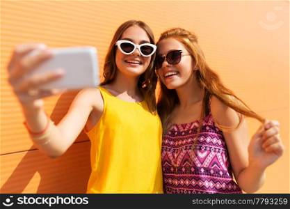fashion, leisure and technology concept - smiling teenage girls taking selfie by smartphone outdoors in summer. teen girls taking selfie by smartphone in summer
