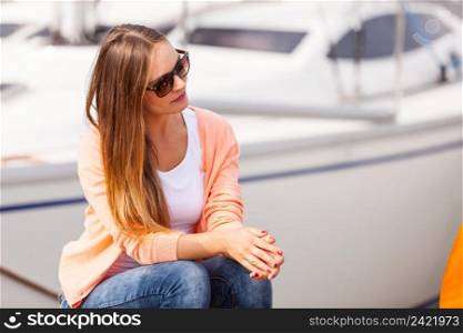 Fashion leisure relax concept. Attractive girl sitting on pier. Young lady enjoying sunny day on coast. . Attractive girl sitting on pier.