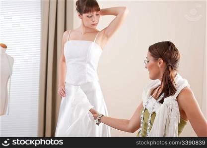 Fashion model fitting white wedding dress in professional fashion designer studio
