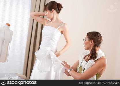 Fashion model fitting white wedding dress in professional fashion designer studio