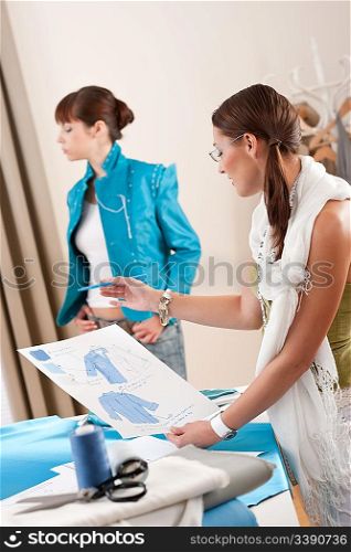 Fashion model trying turquoise jacket in professional designer studio