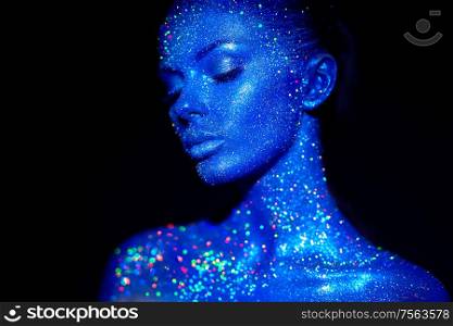 Fashion model woman in blue bright sparkles and neon lights posing in studio. Portrait of beautiful sexy woman. Art design colorful glitter glowing make up
