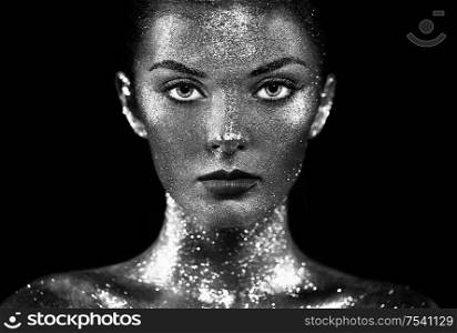 Fashion model woman in bright sparkles and lights posing in studio. Portrait of beautiful sexy woman. Art design glitter glowing make up. Black and white photography