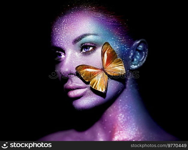 Fashion model woman in bright sparkles and neon lights posing in studio. Portrait of beautiful woman with butterfly. Art design glitter glowing make up